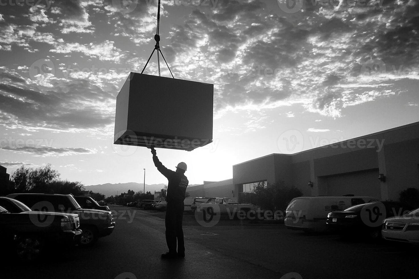 A man lifting a large box from a parking lot photo