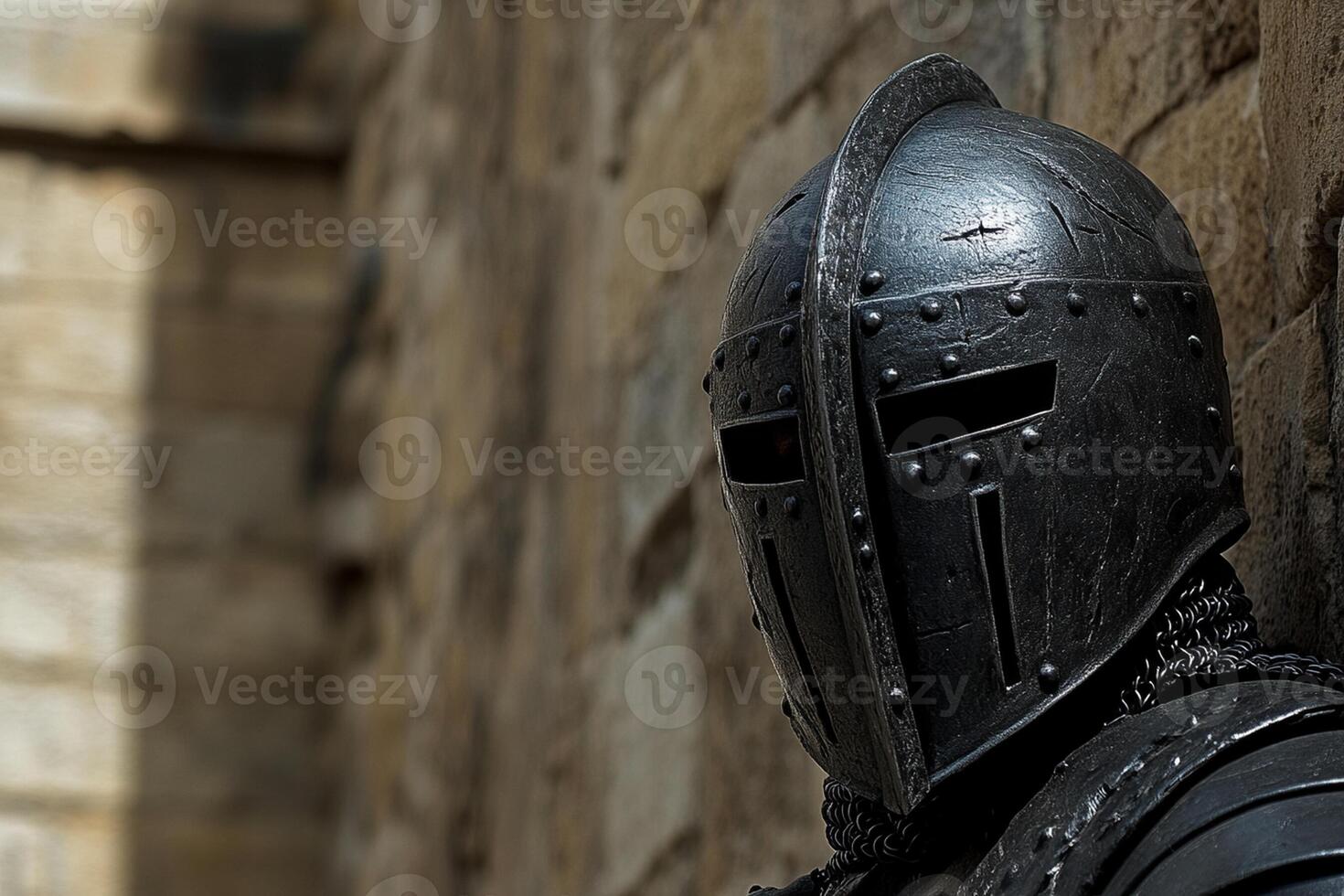 A knight in armor standing against a wall photo
