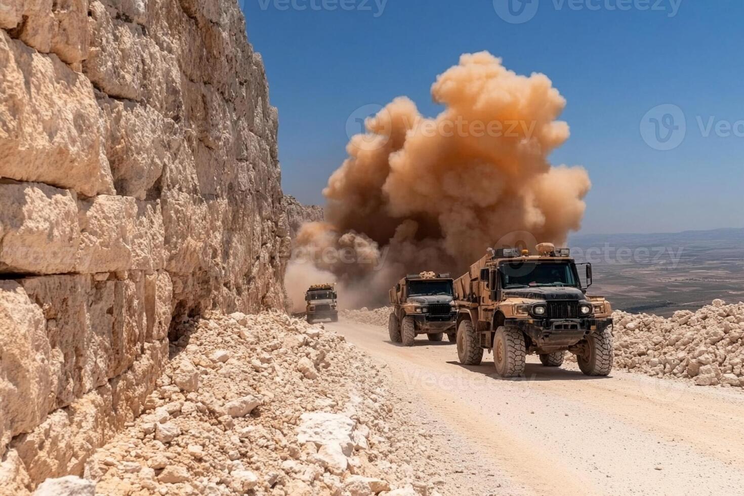 A military convoy drives down a dirt road photo