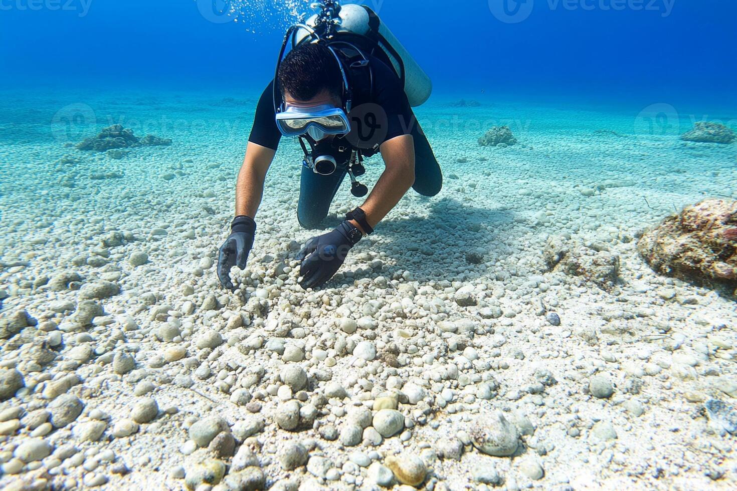 A scuba diver in the ocean looking at rocks photo