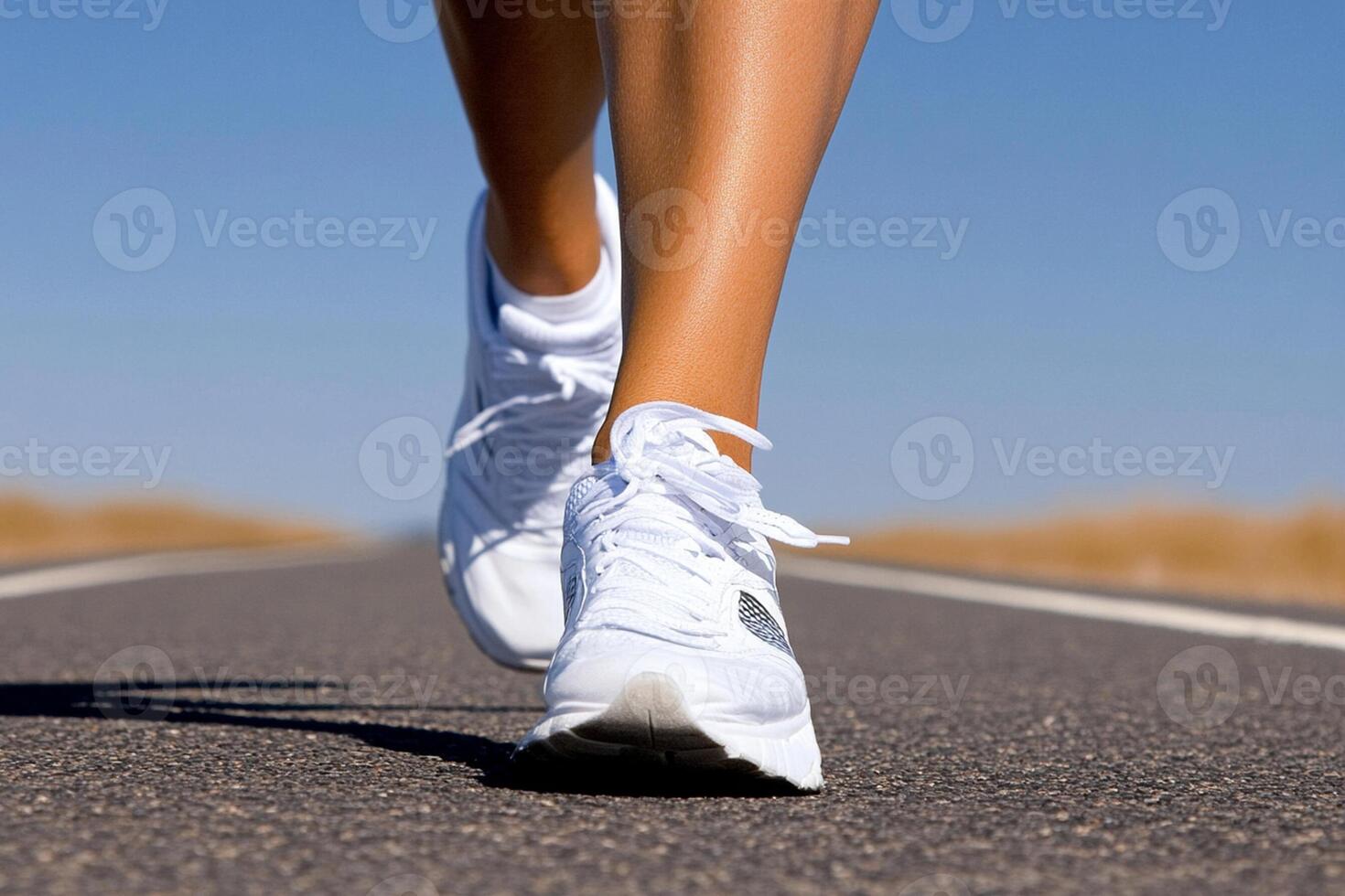 A person wearing white tennis shoes is running on a road photo
