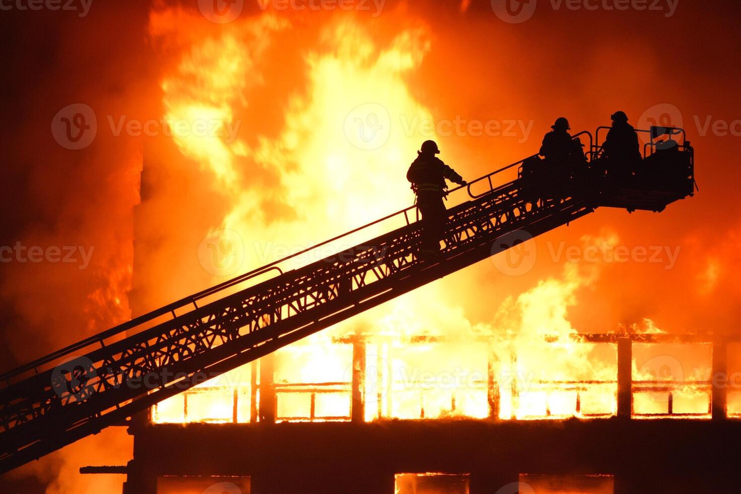 Firefighters on a ladder at night with a large fire photo