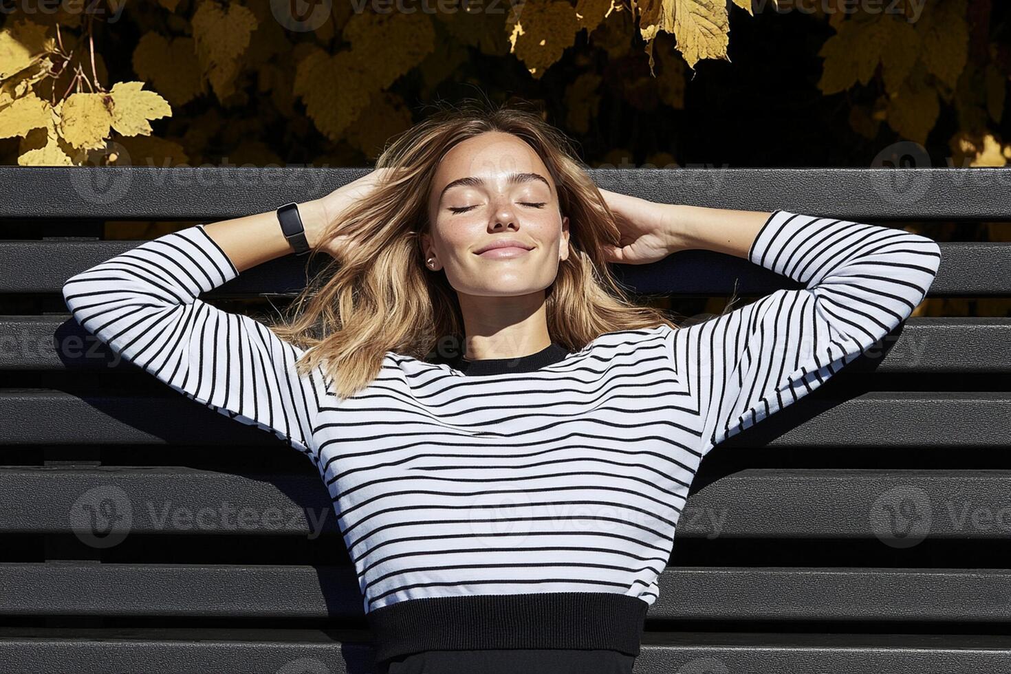 A woman in a striped shirt is laying on a bench photo