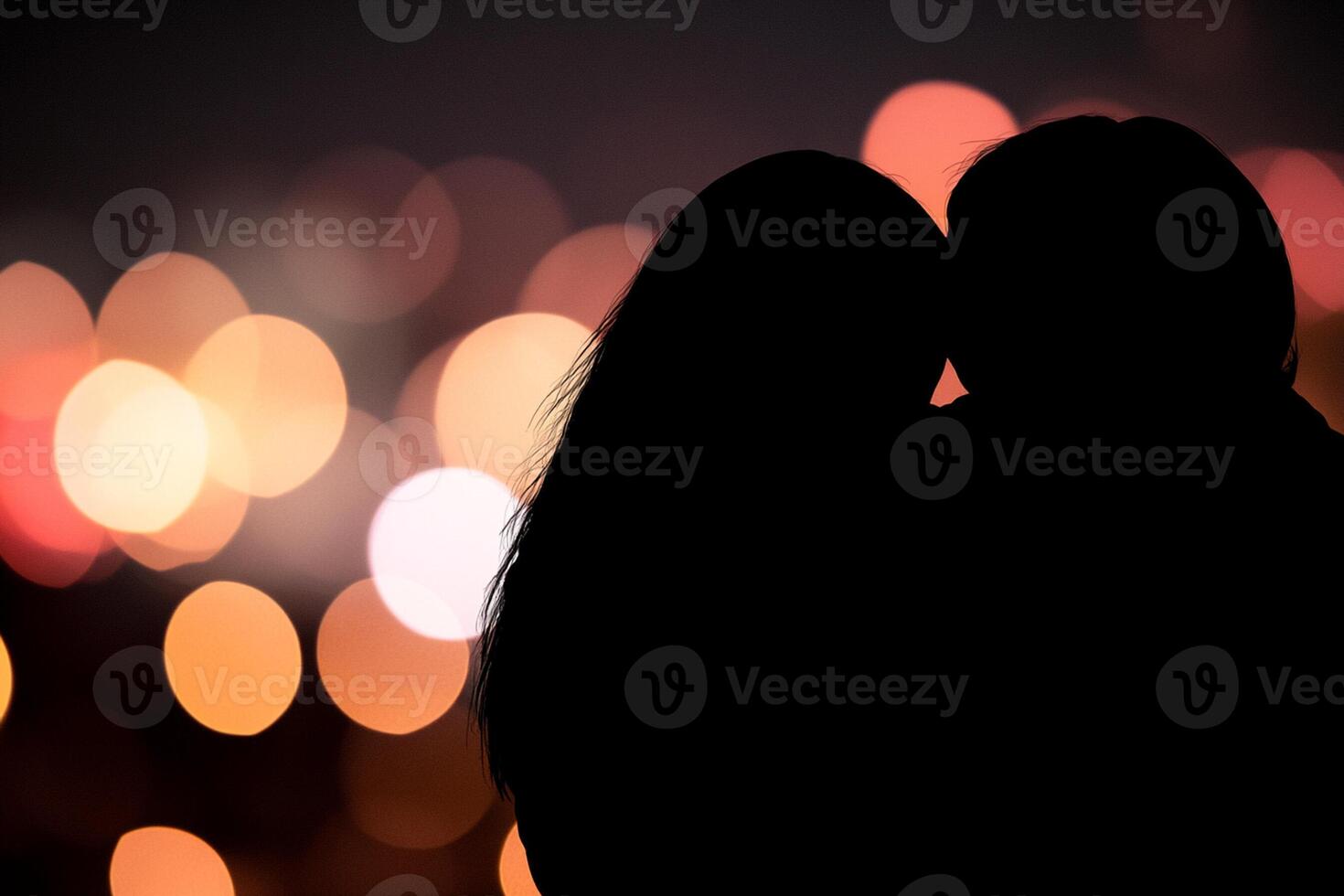 A couple is silhouetted against the lights of a city photo