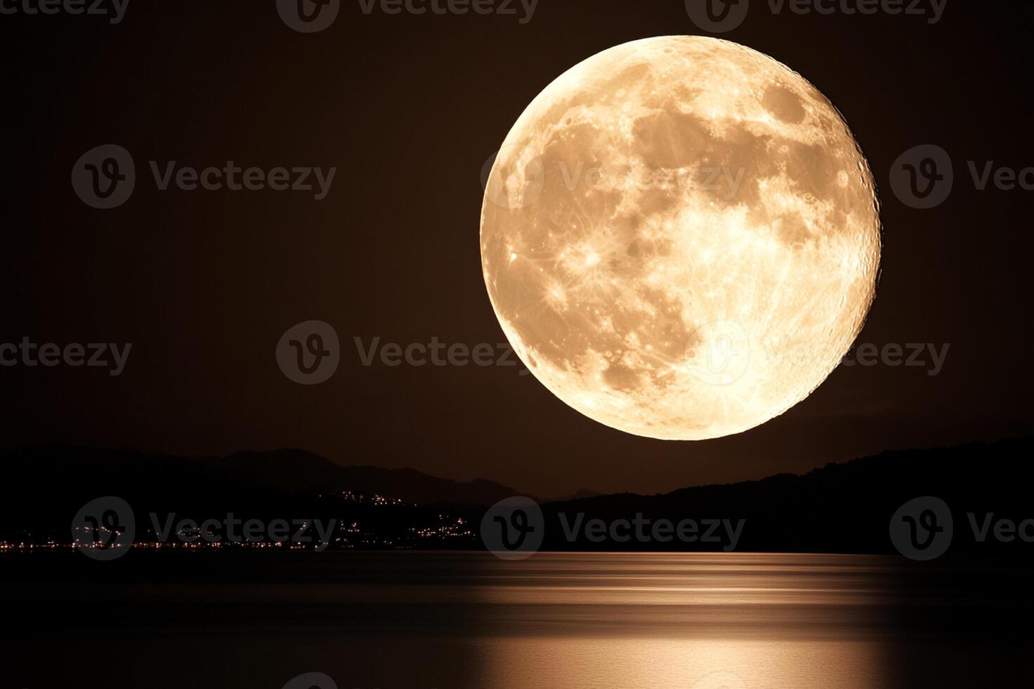 The moon is reflected in the water as it rises over the mountains photo