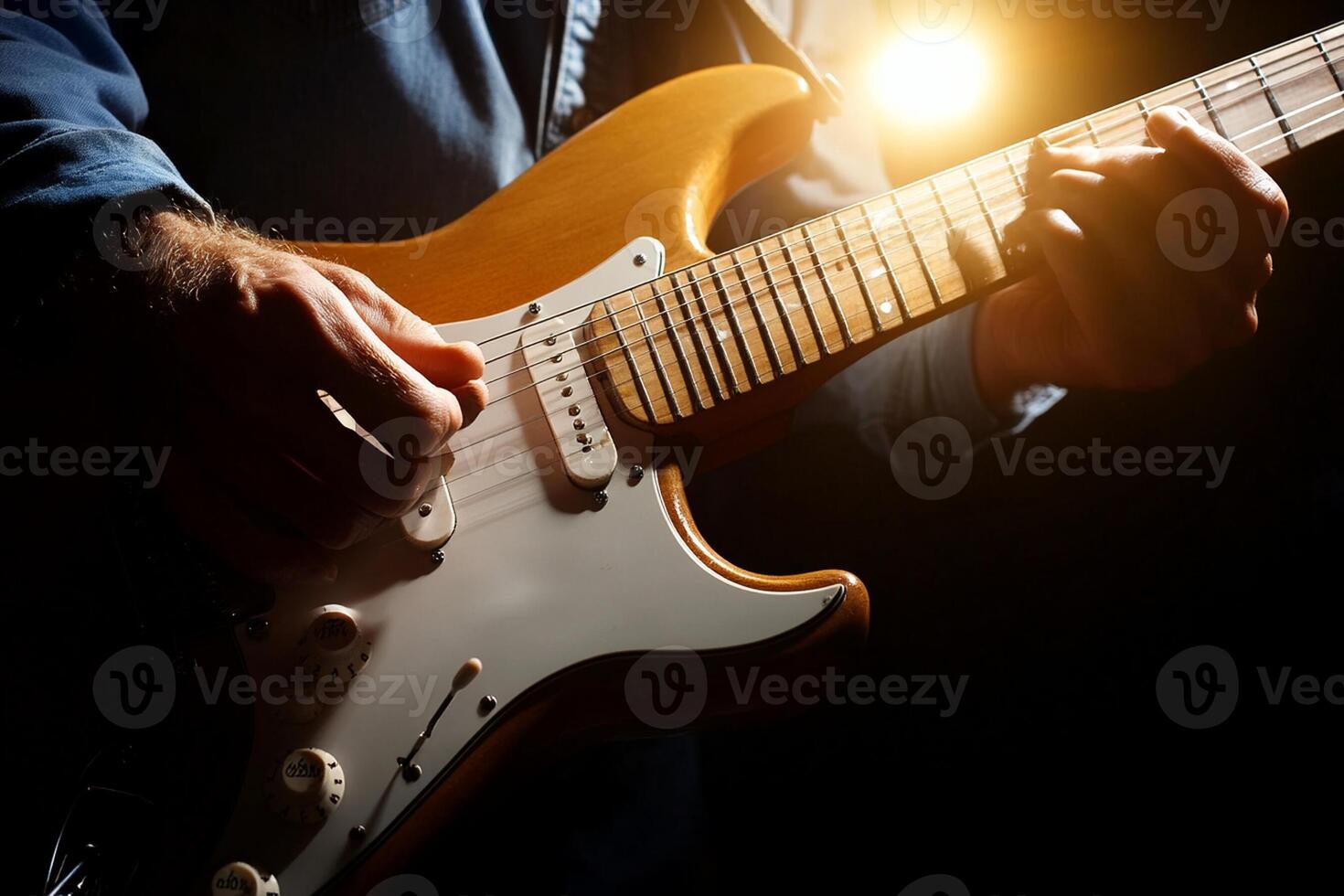 A man is playing an electric guitar in front of a spotlight photo