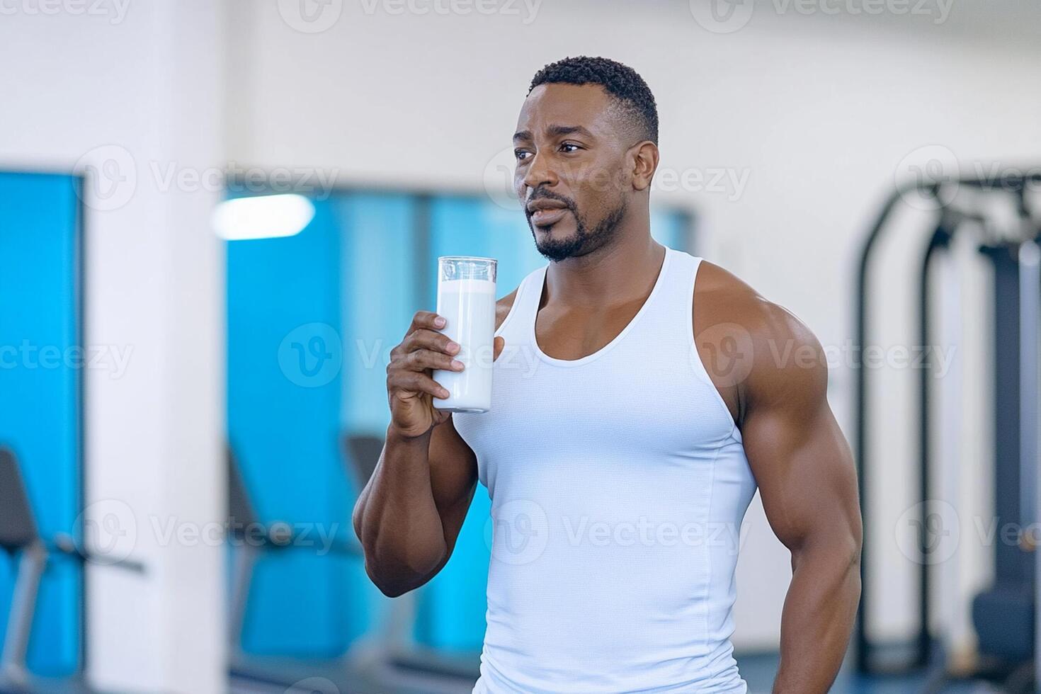 A man is holding a bottle of water in a gym photo