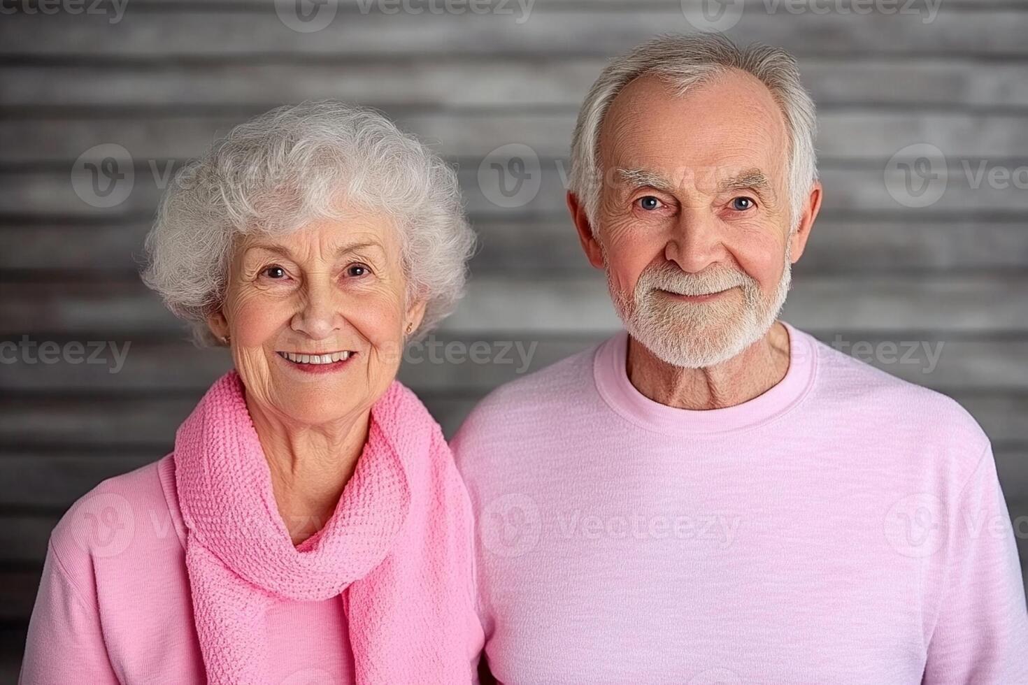 An older couple in pink shirts posing for the camera photo