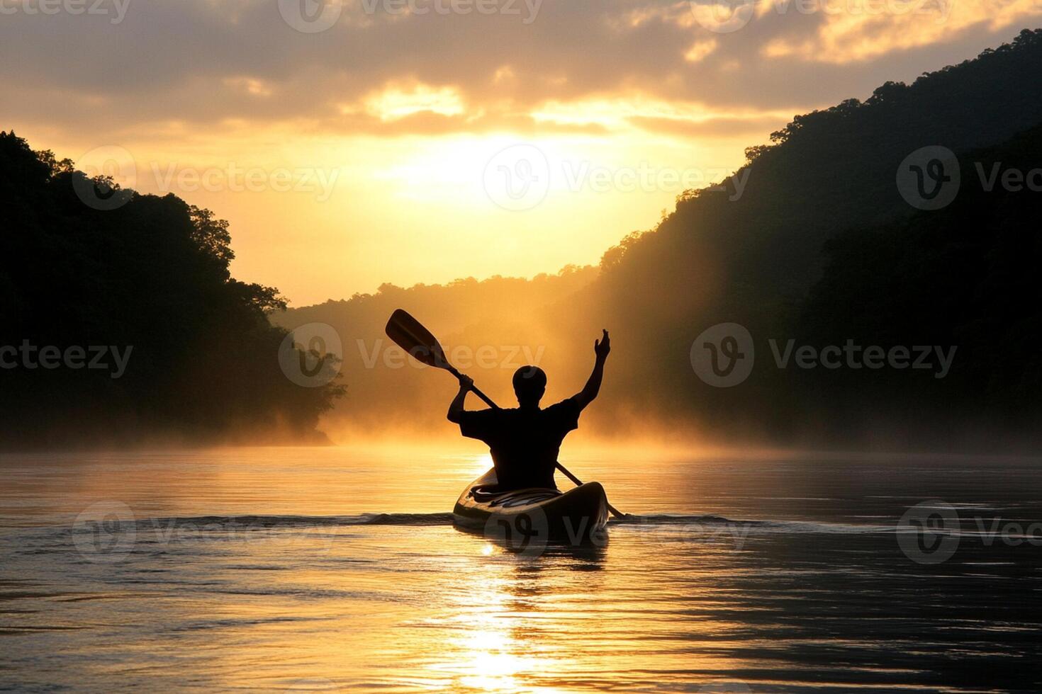 A man paddles a canoe on a river at sunset photo