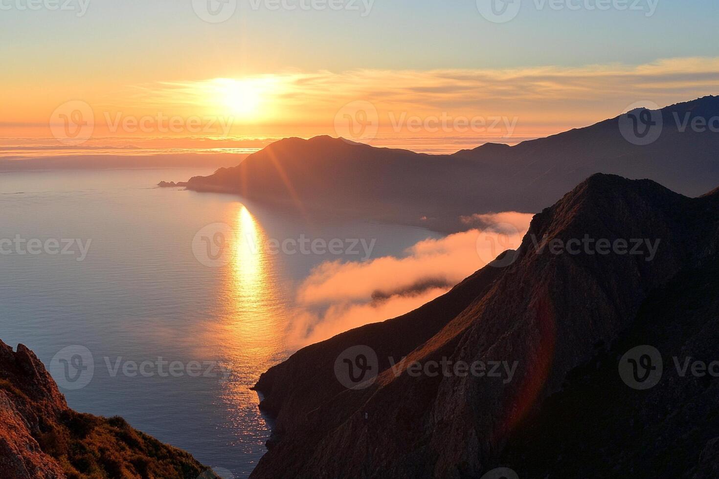 The sun rises over the ocean and mountains photo