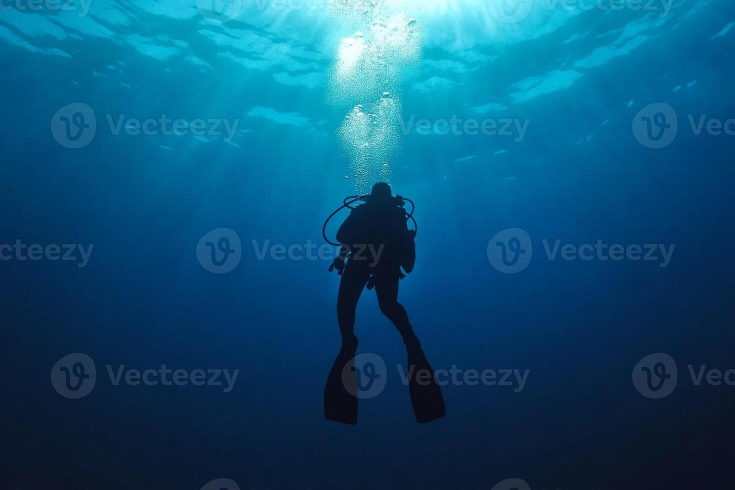 A scuba diver in the ocean with sunlight shining through photo