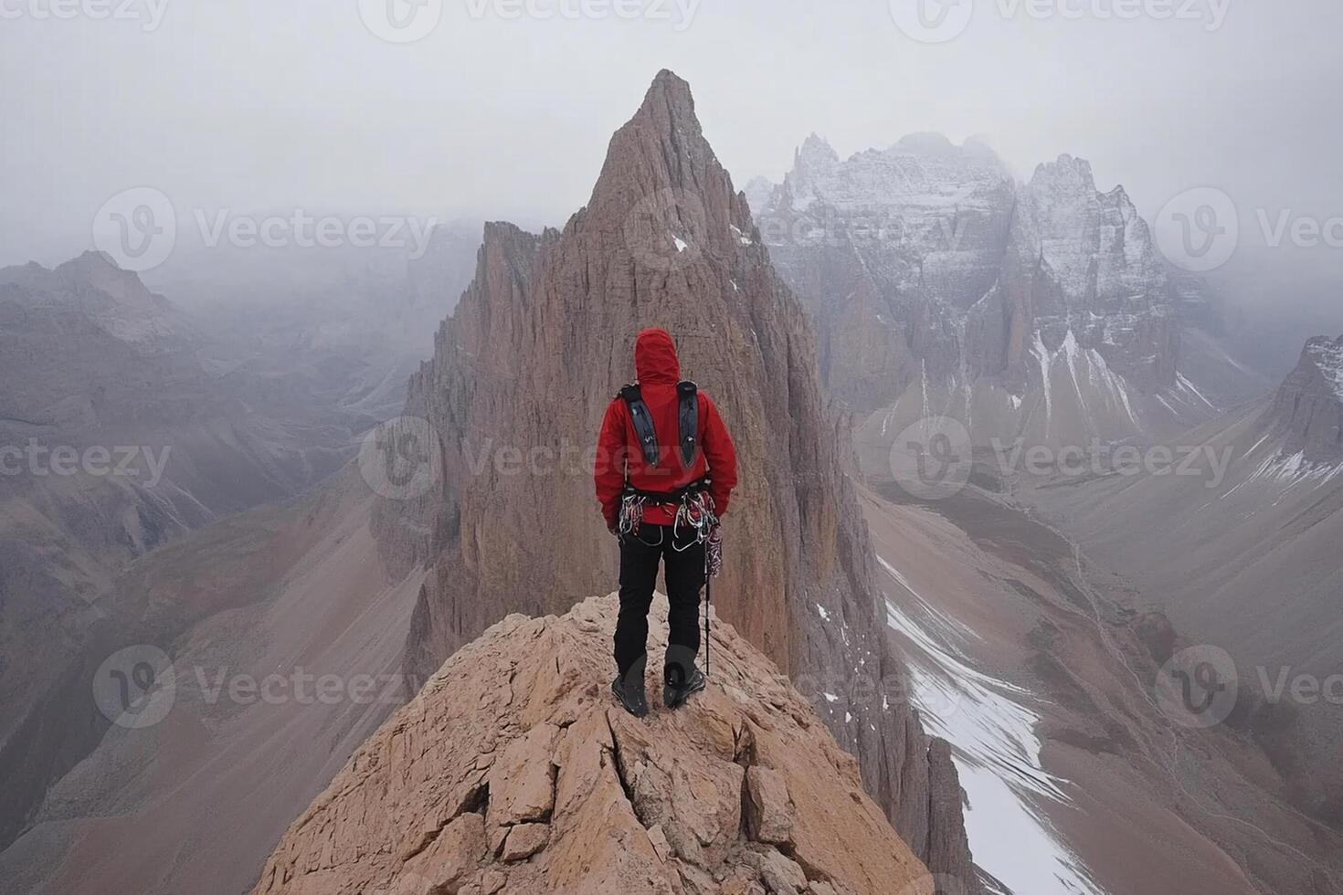 A person standing on top of a mountain with a red jacket photo