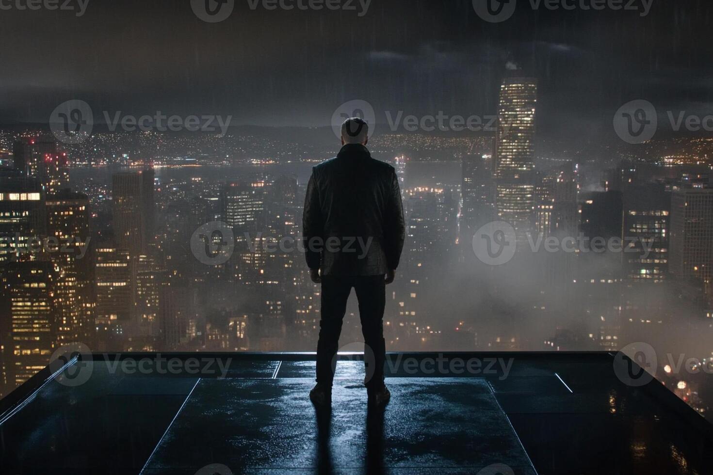 A man standing on a roof looking at the city at night photo