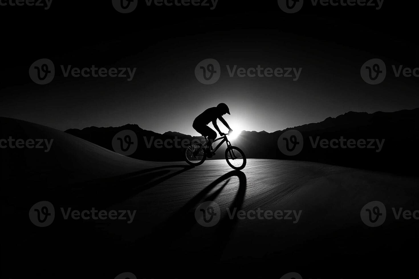 A man riding a bike on a desert hill at night photo