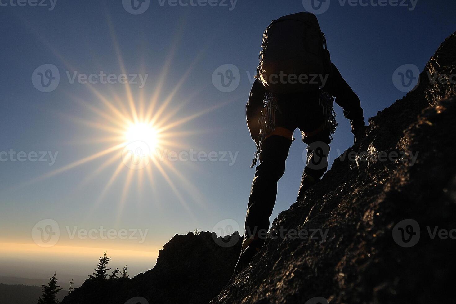 A person climbing up a mountain with the sun in the background photo
