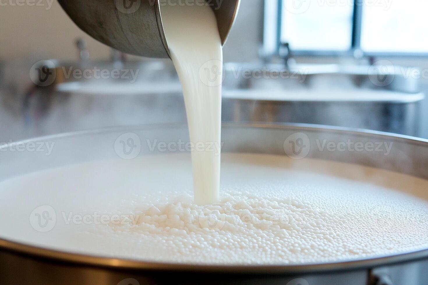 A person pouring milk into a large metal pot photo