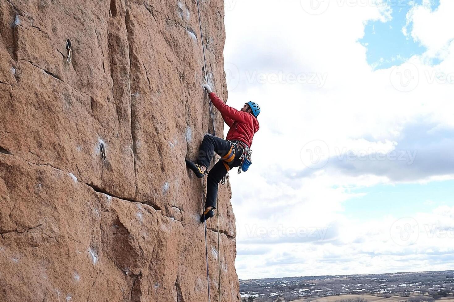 A man on a rock climbing wall with a blue sky photo