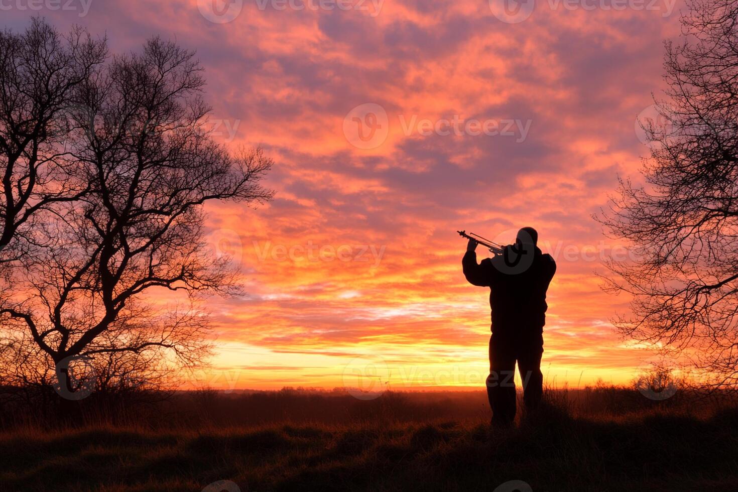 A man holding a rifle at sunset photo