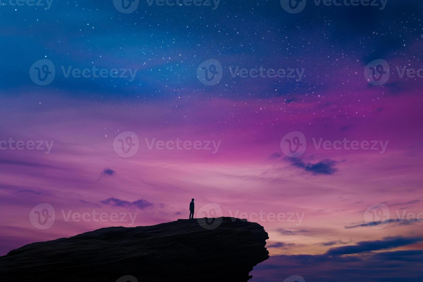Man standing on top of a cliff looking at the sky photo