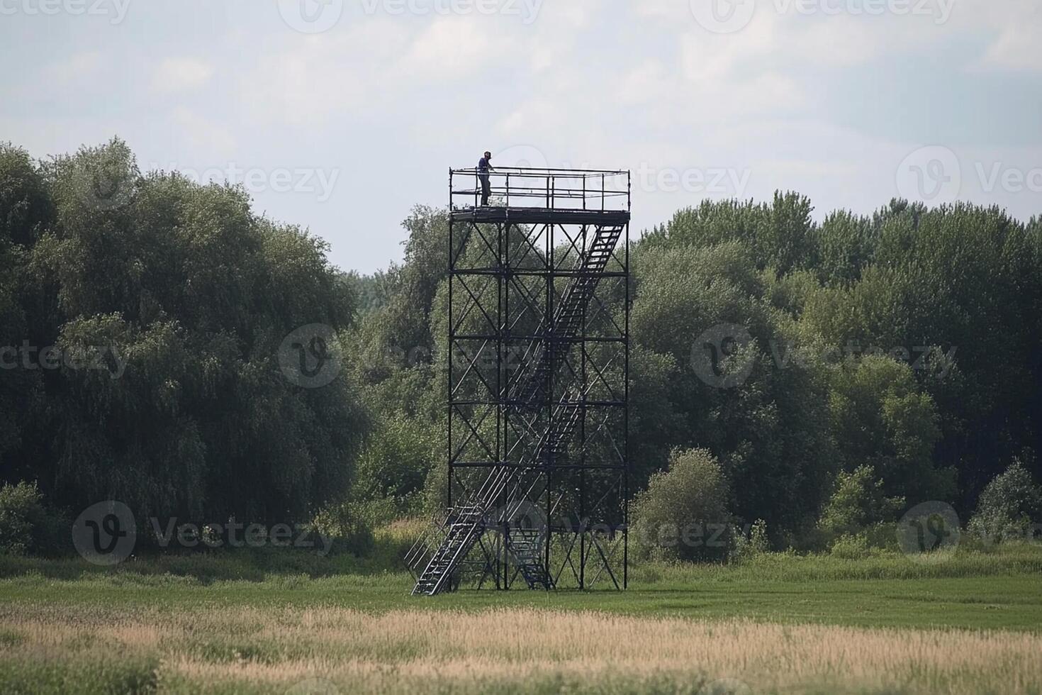 A man standing on top of a tall metal tower photo