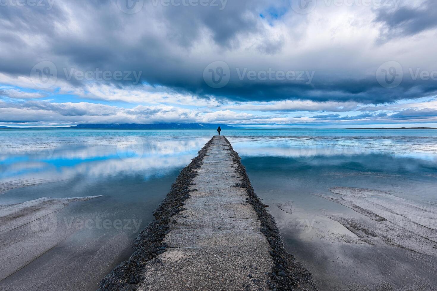 A long pier with a cloudy sky and water photo