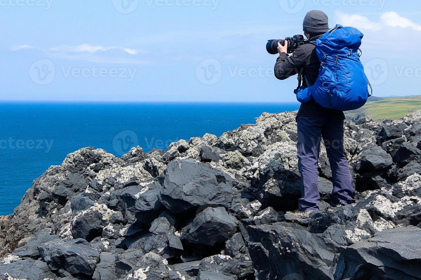A man with a backpack standing on a rocky hill photo