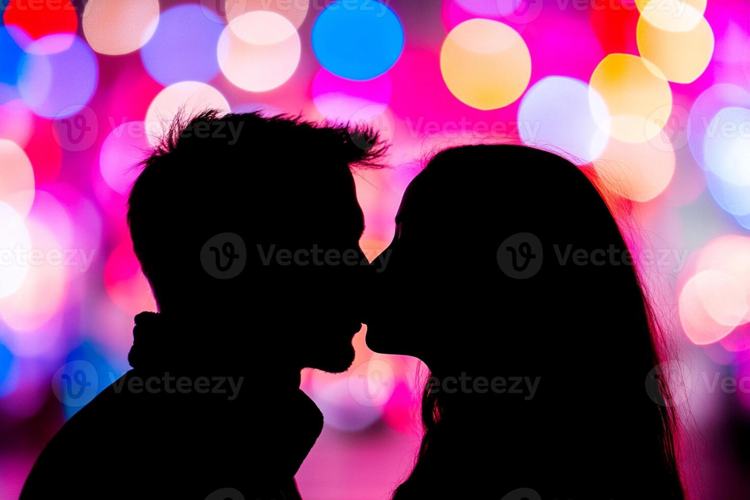 A couple kissing in front of colorful lights photo