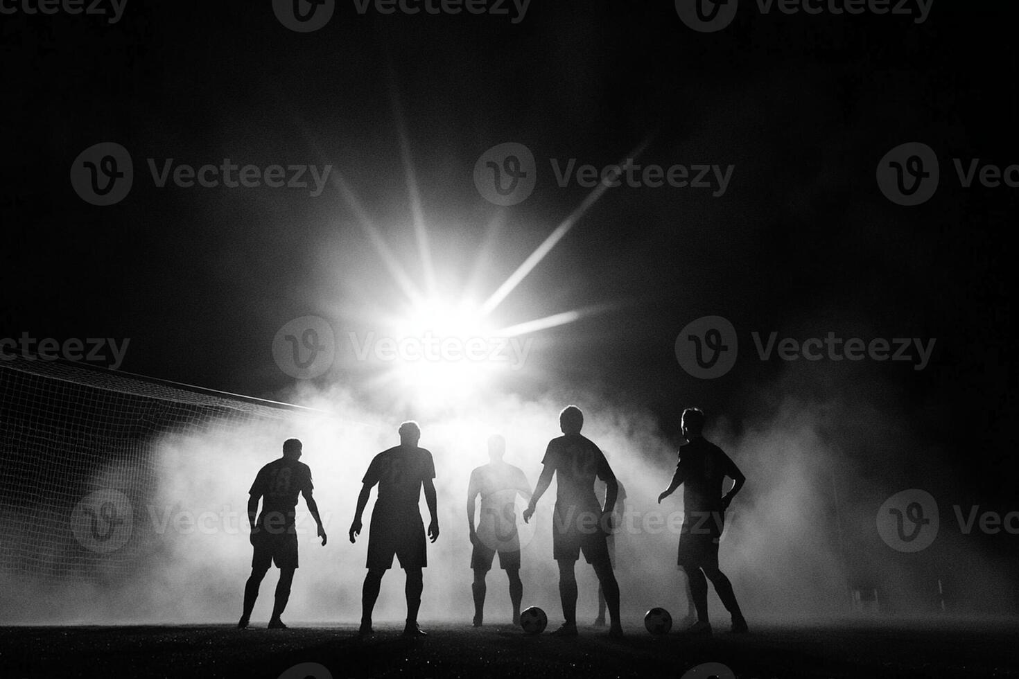 A group of soccer players standing in the dark with a light shining on them photo