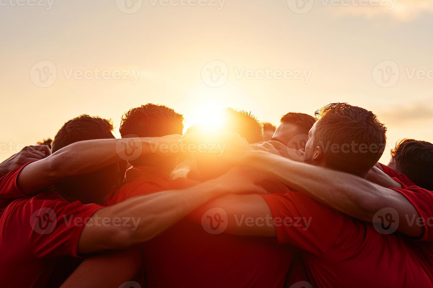 A group of people in red shirts are huddled together photo