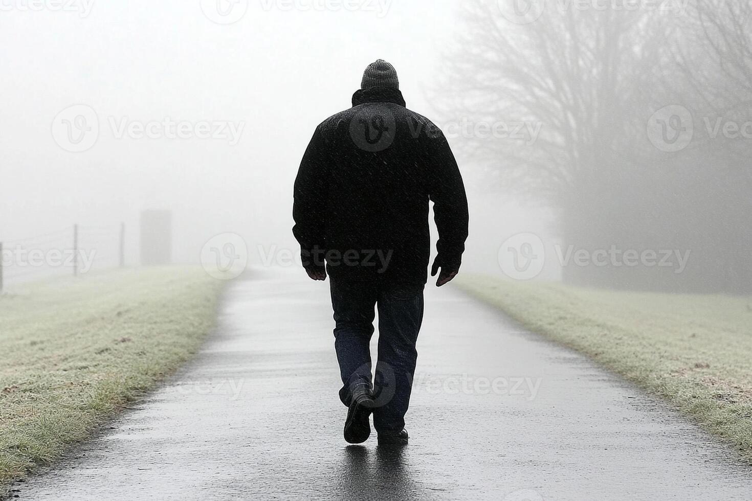 A man walking down a path in the fog photo