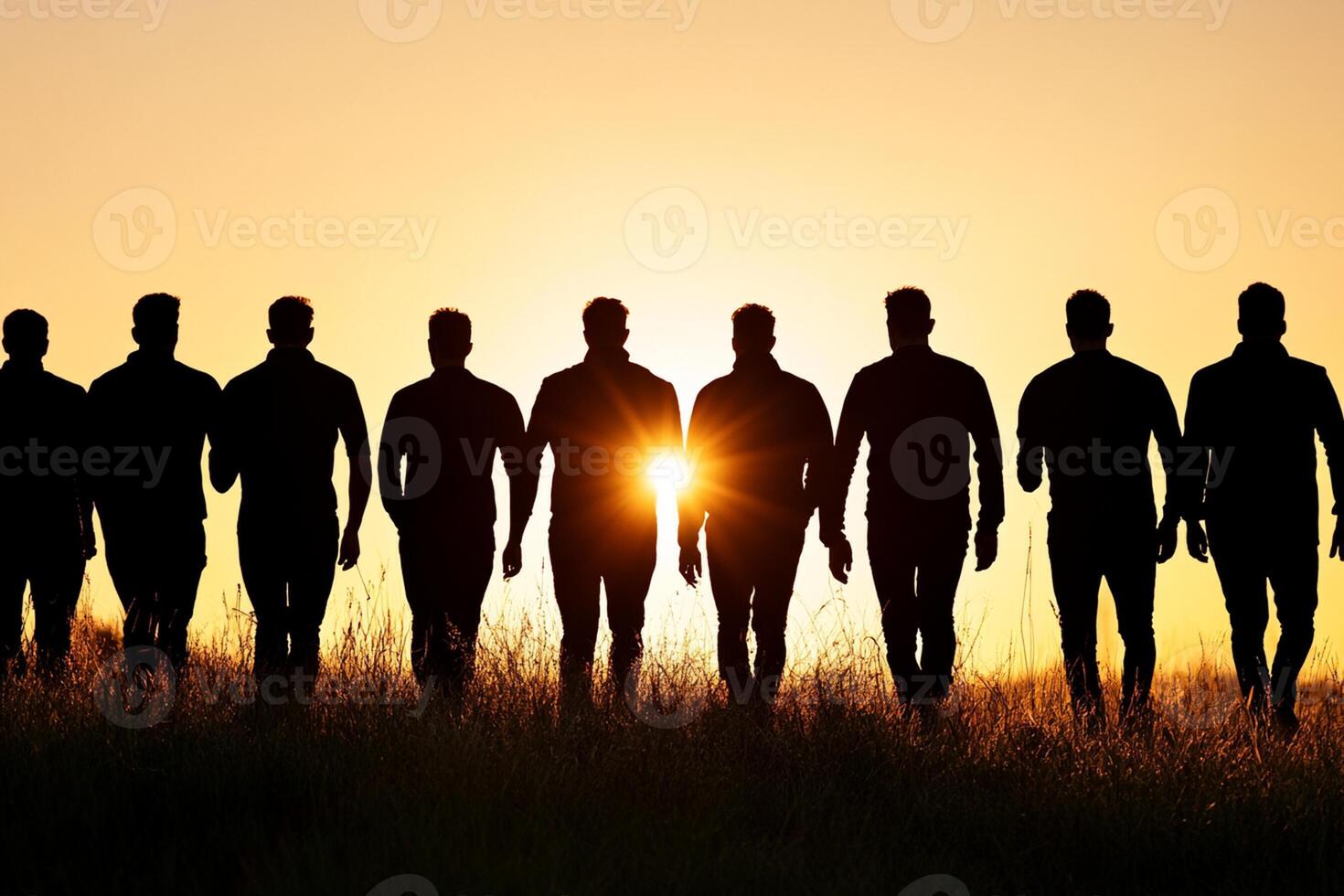 Silhouette of a group of men walking in a field at sunset photo