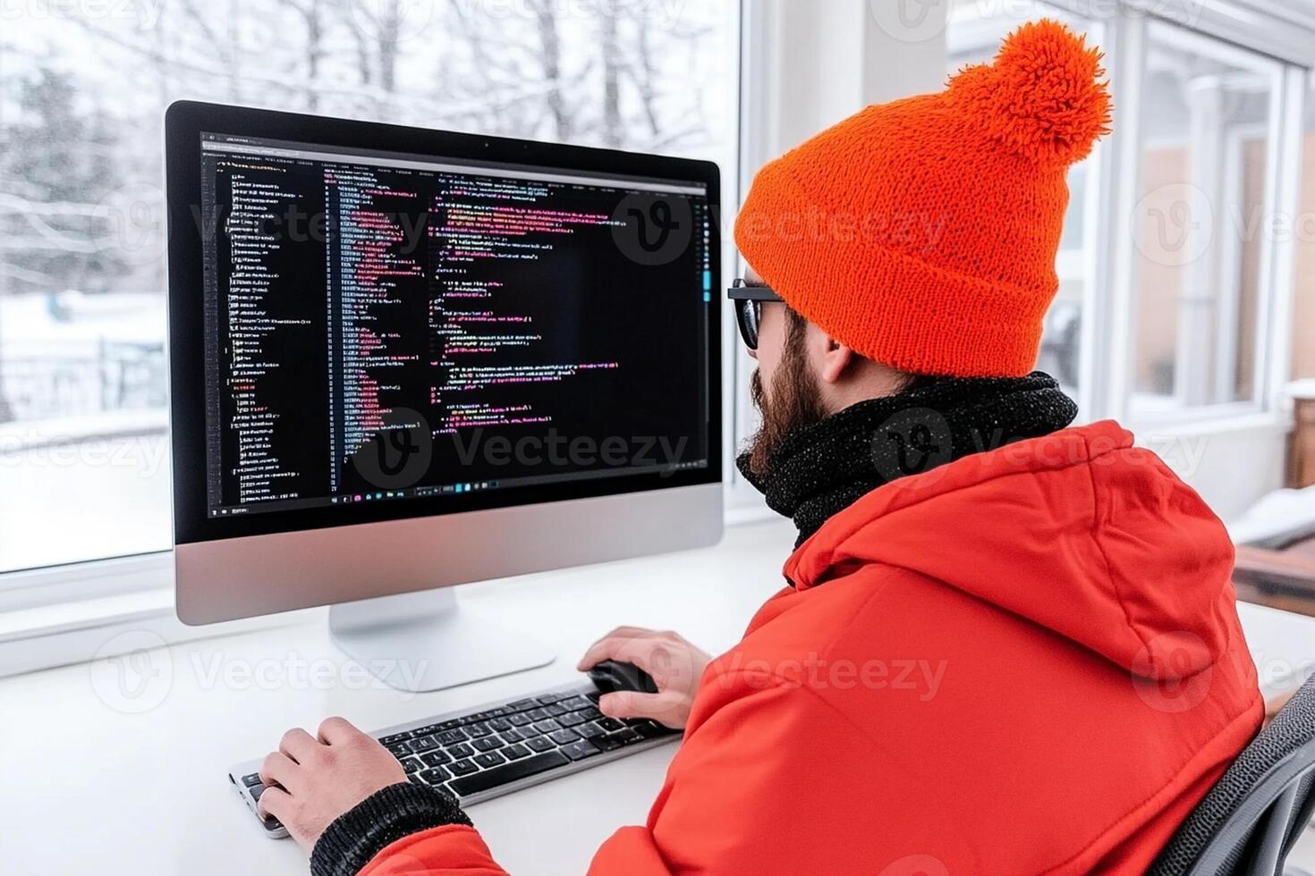 A man wearing an orange hat is working on a computer photo