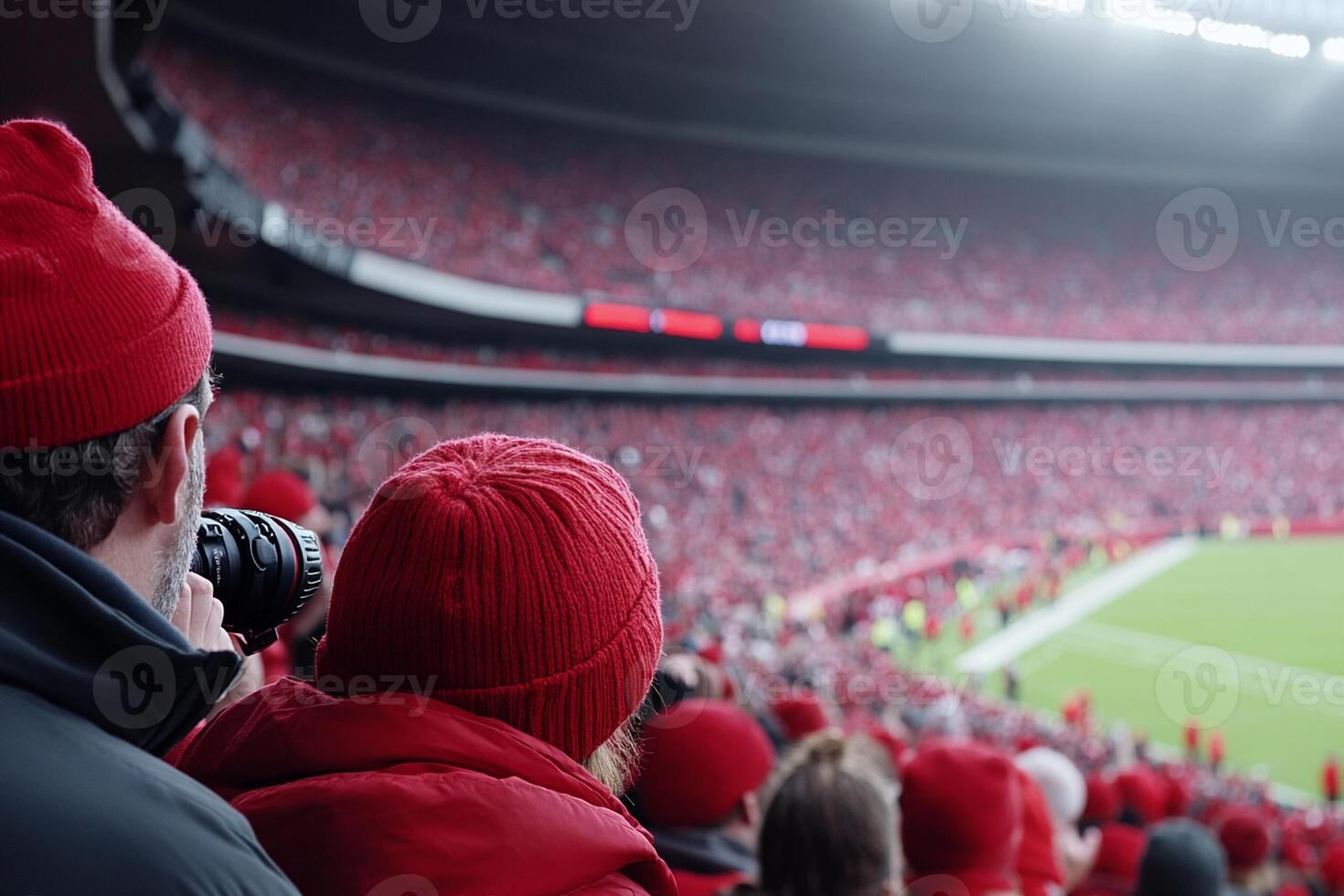 A group of people in red hats and hats watching a football game photo