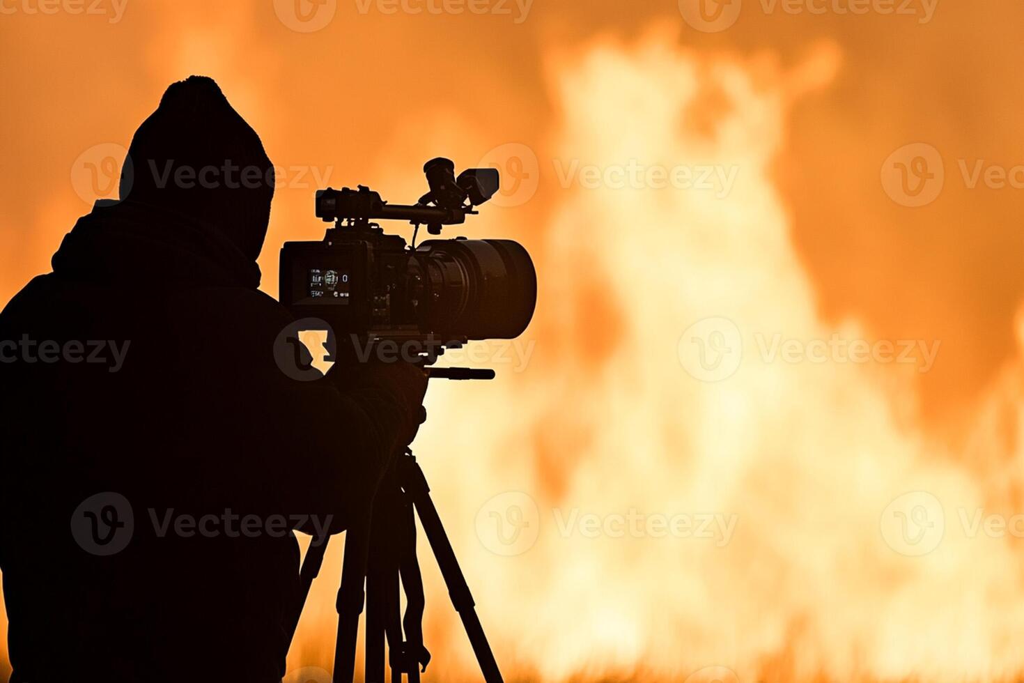 A man is holding a camera in front of a fire photo