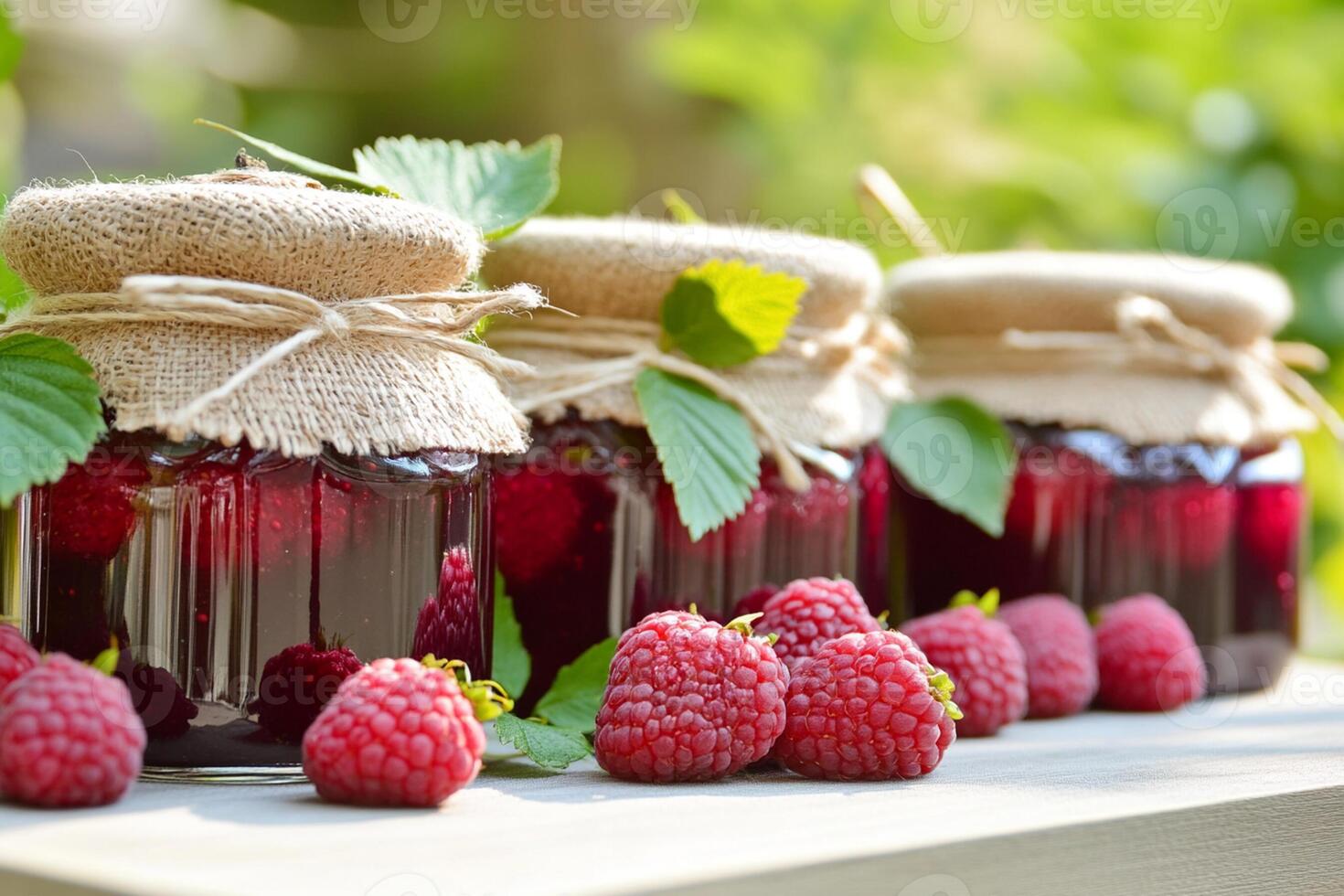 Three jars of raspberry jam with berries on a wooden table photo