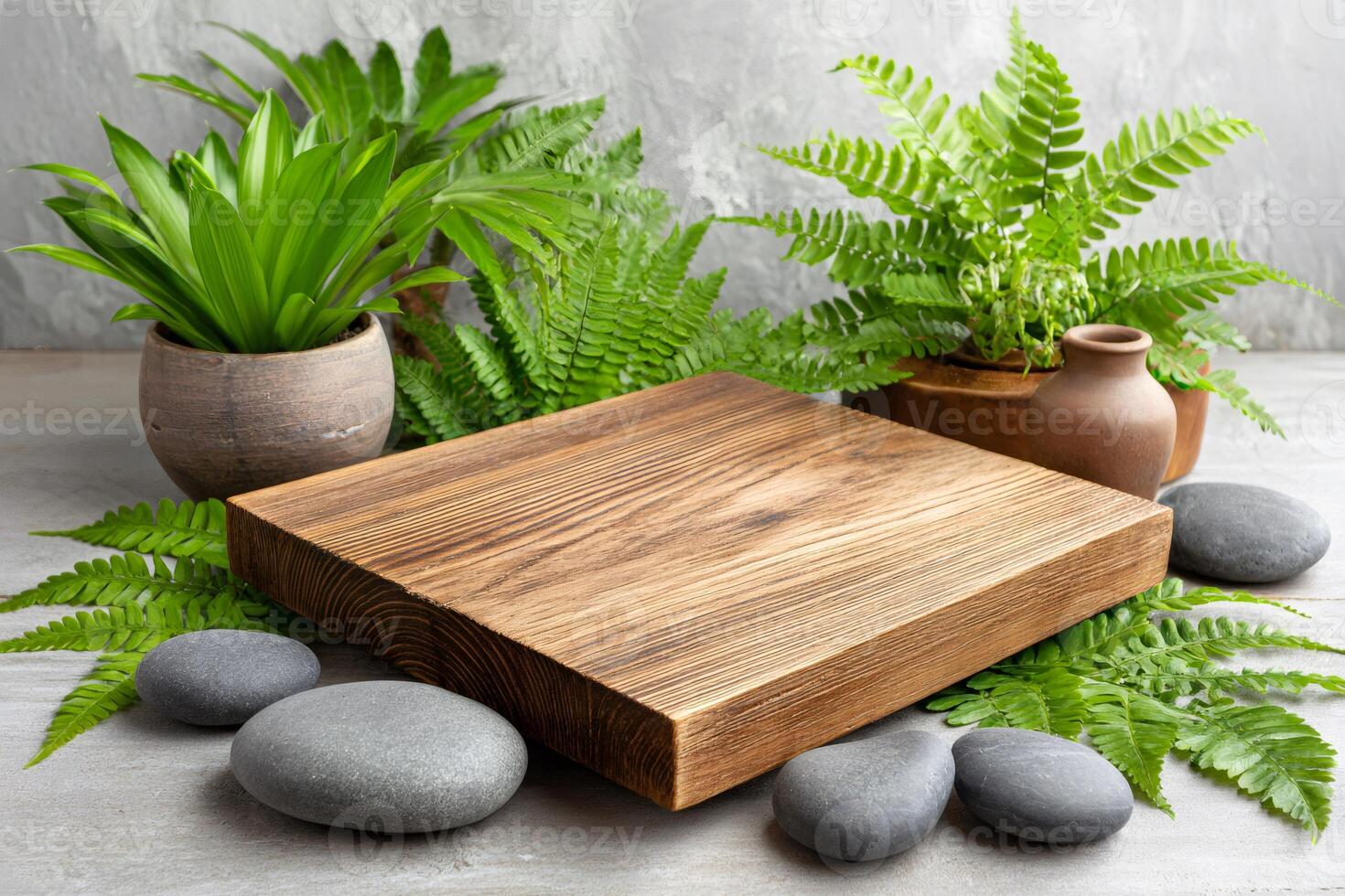 Empty wooden board displaying with green plants and stones on concrete background photo