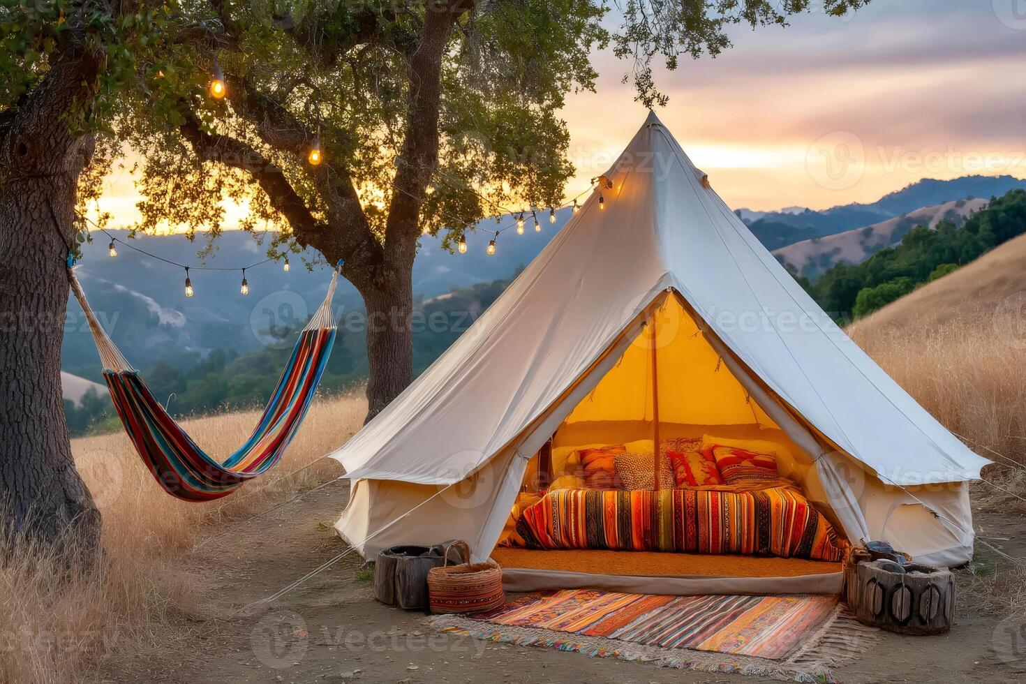 Illuminated tent and hammock under trees at sunset in a glamping site photo