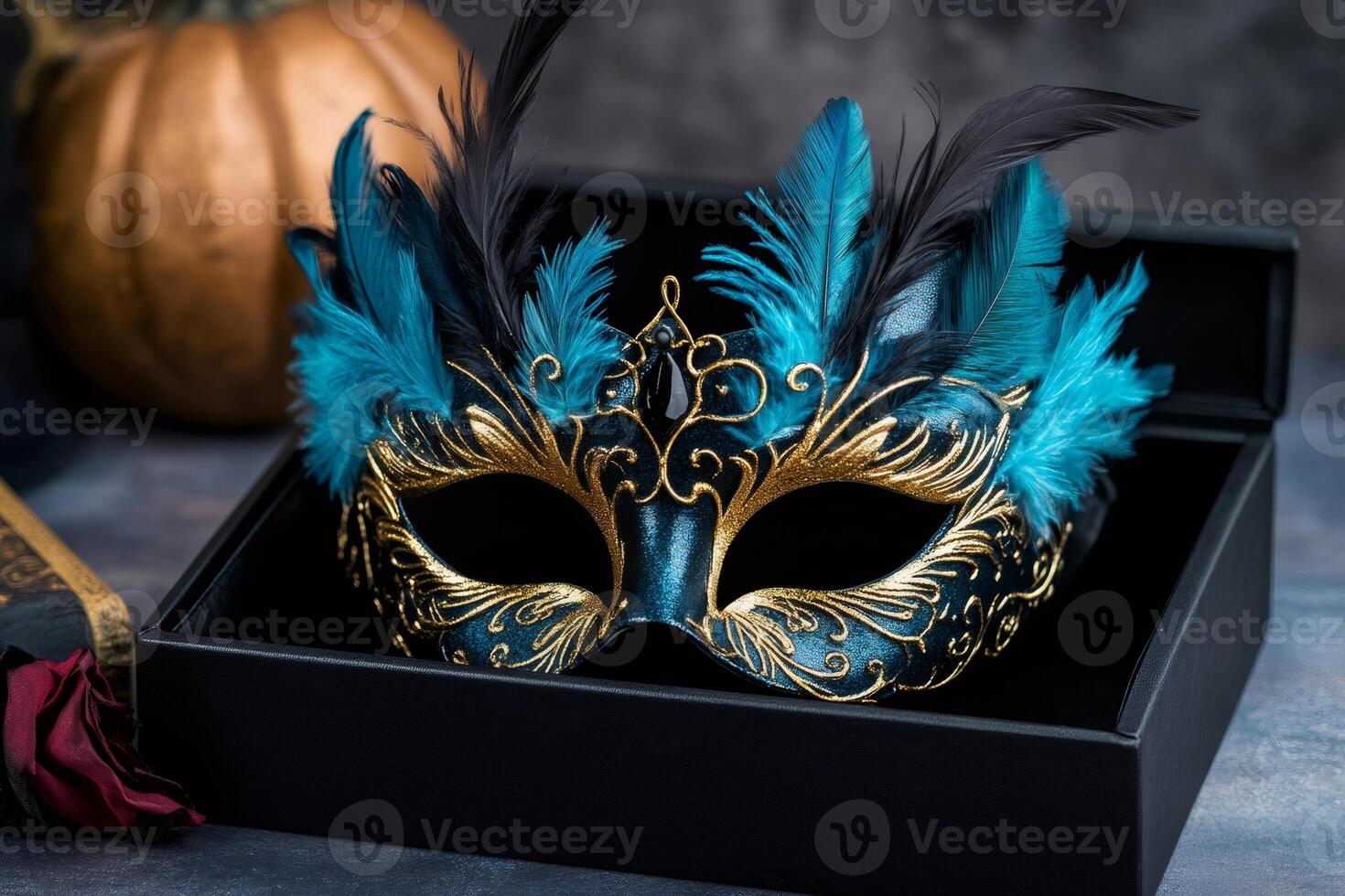 Elegant turquoise and gold masquerade mask with feathers resting in a black box photo