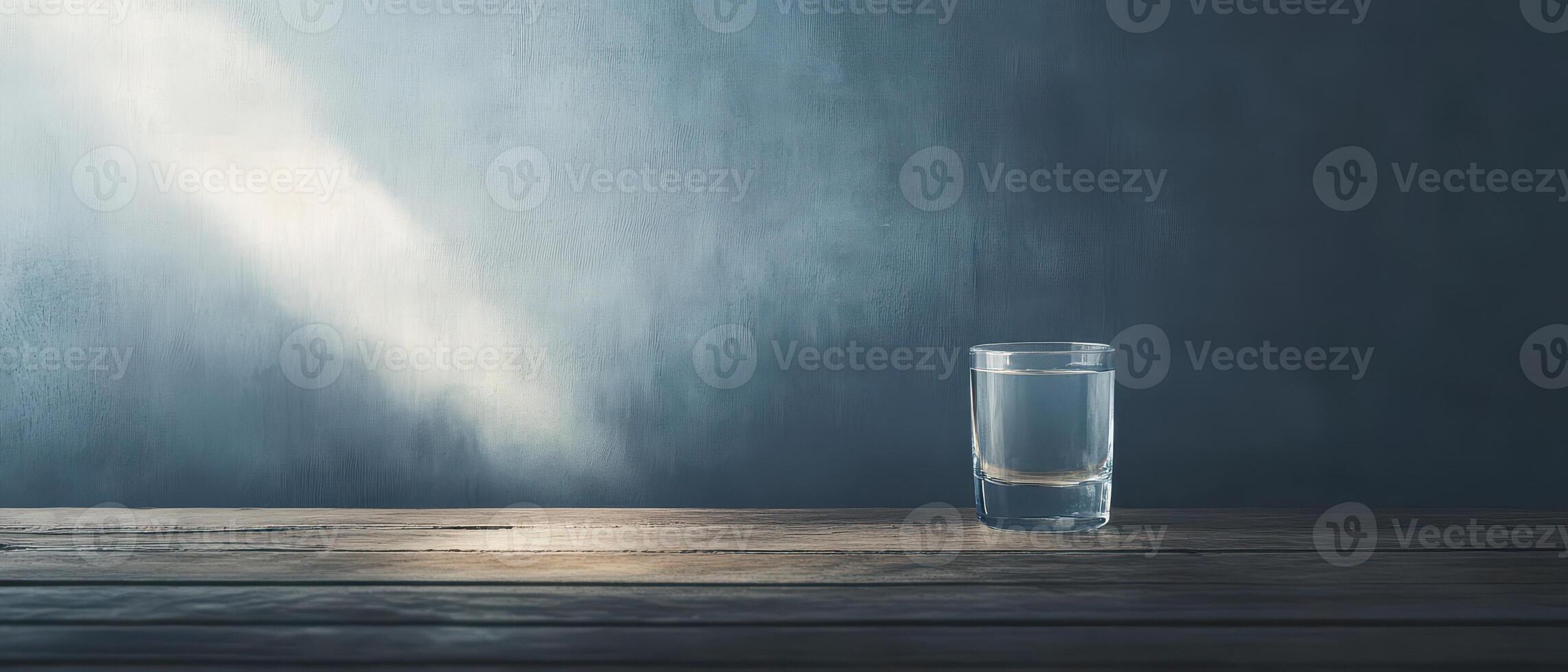 Glass of water on a wooden table with light rays photo