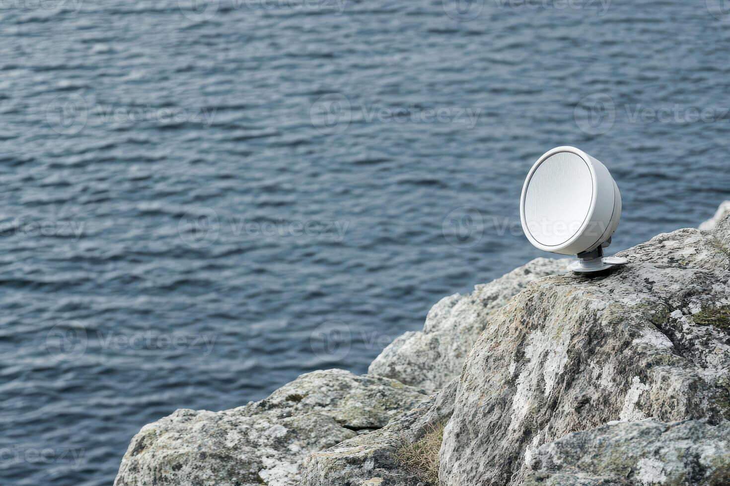Spotlight on rocky shore by ocean photo