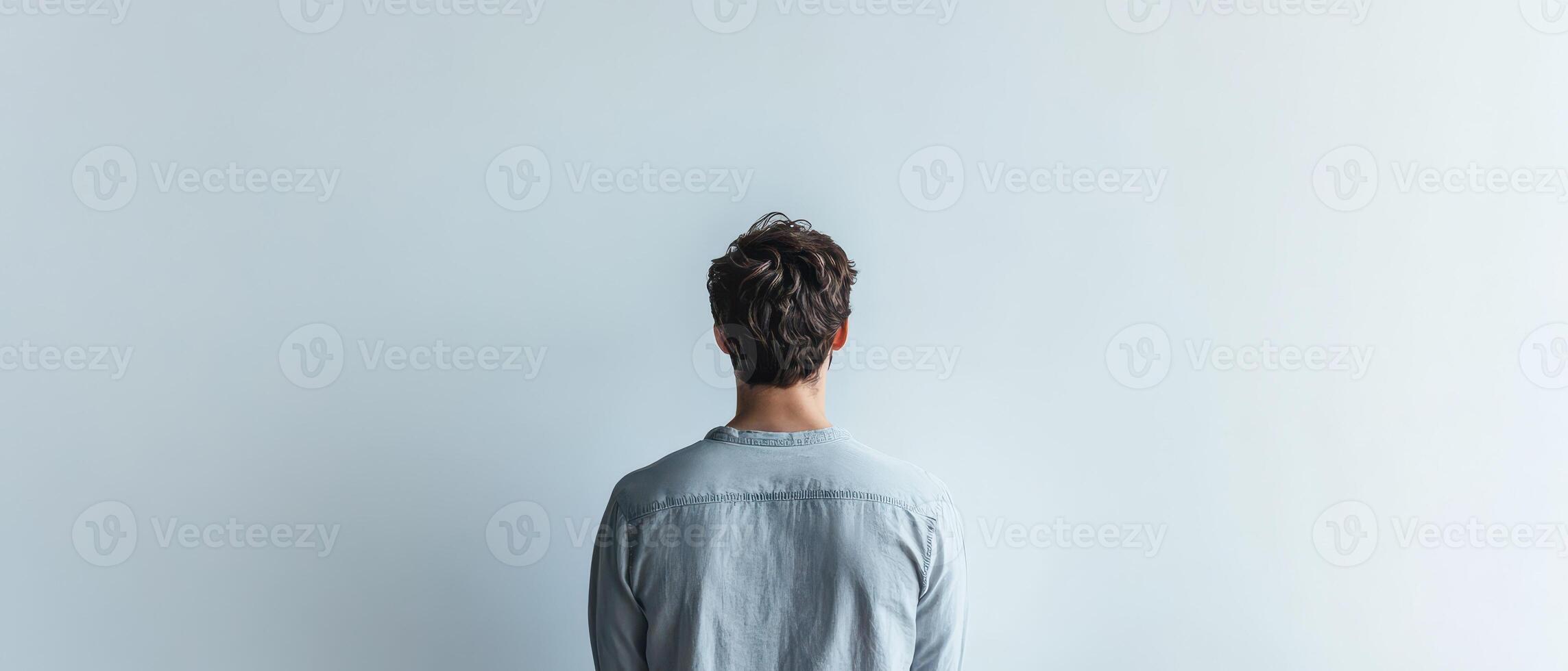 Person standing alone in front of blank wall photo