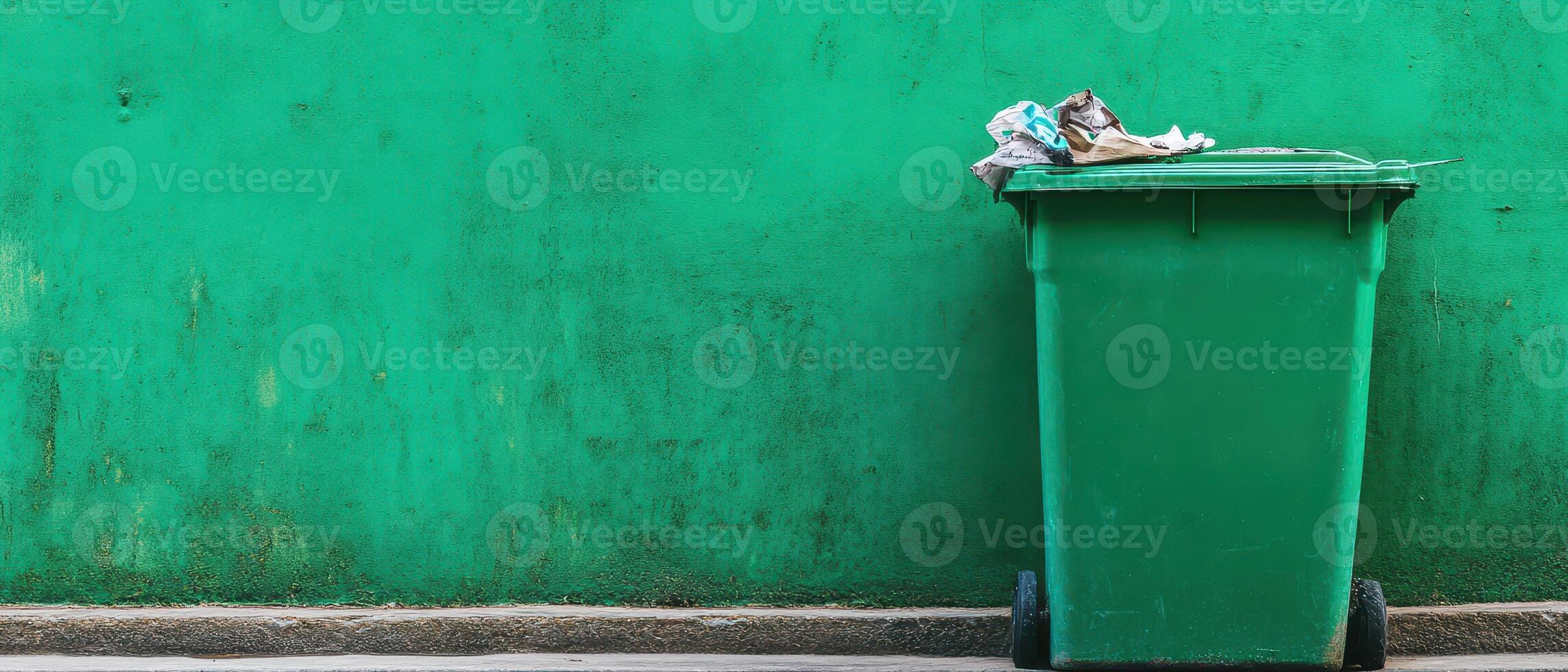 A green trash can sitting on the side of a street photo