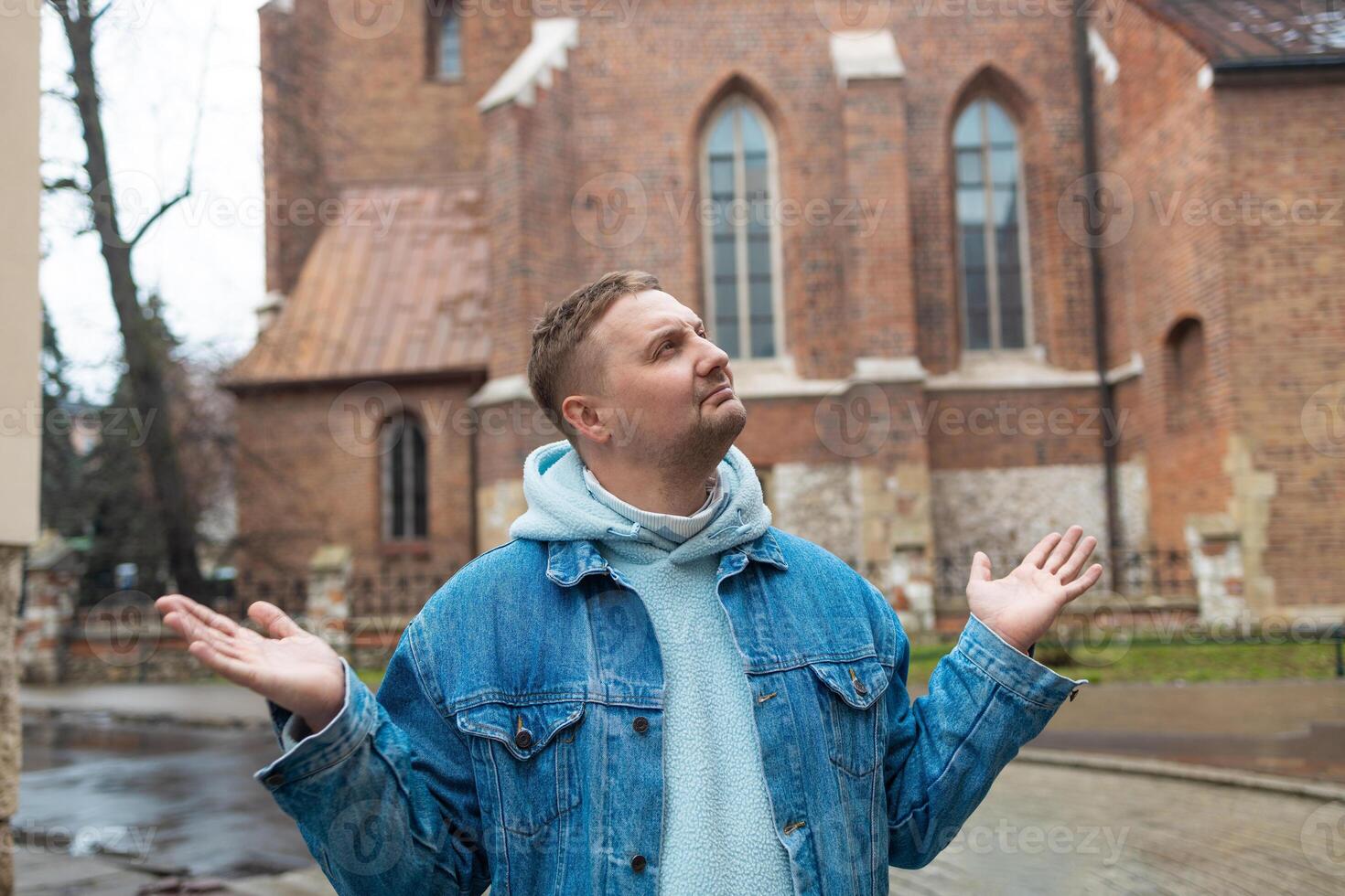 Man Shrugging Outdoors in Front of Historic Building photo