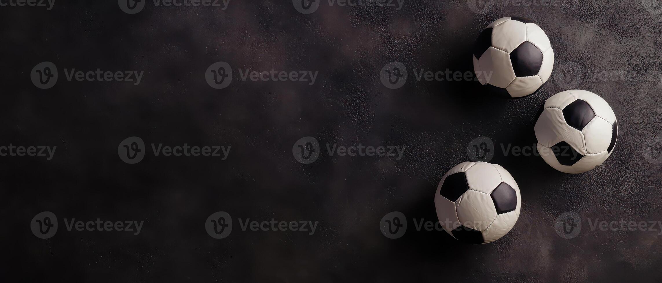 Black and white soccer balls on dark surface photo