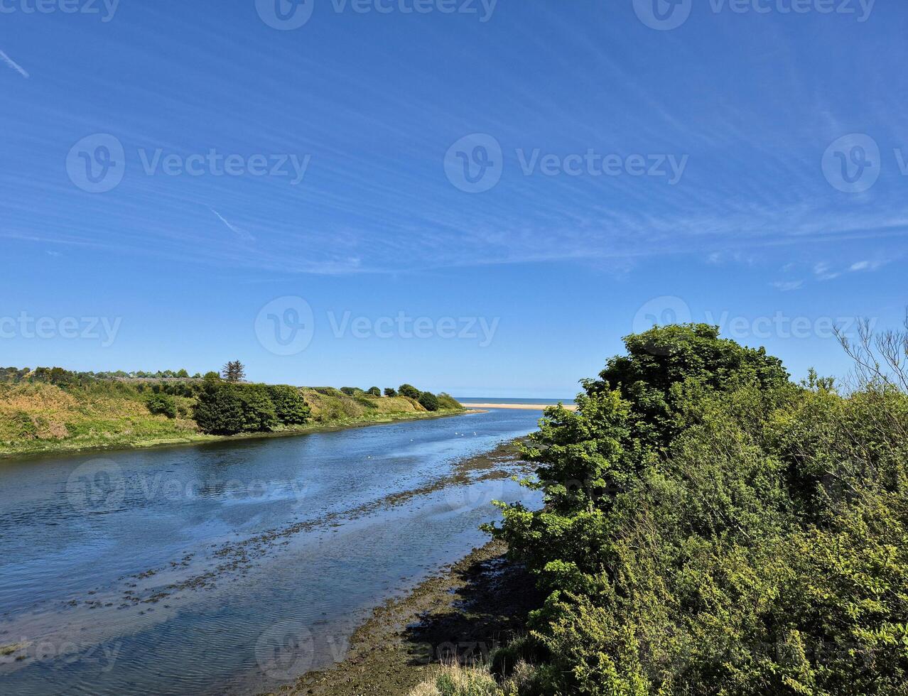 serene river or estuary flowing toward the sea, bordered by lush greenery photo