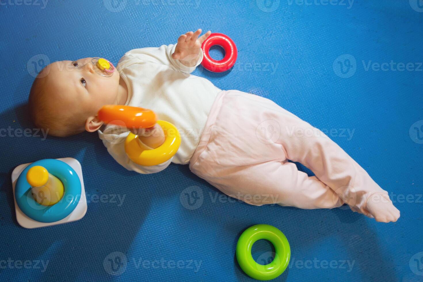 The child plays on the pyramid lying on the floor photo