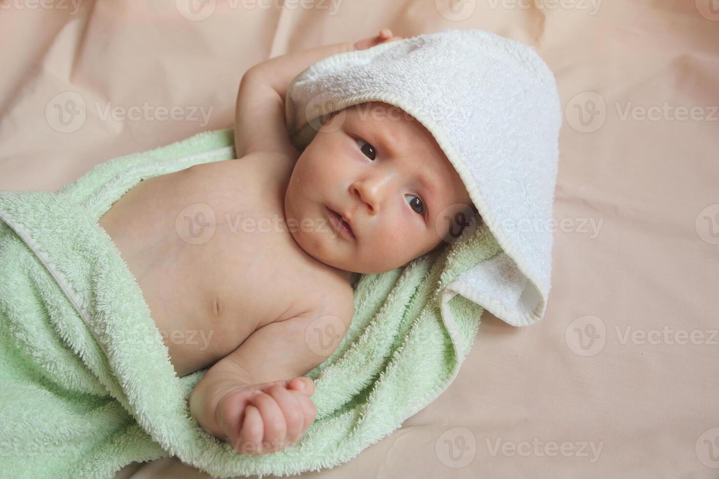 Cute little naked newborn child lies on a soft sheet under a towel photo