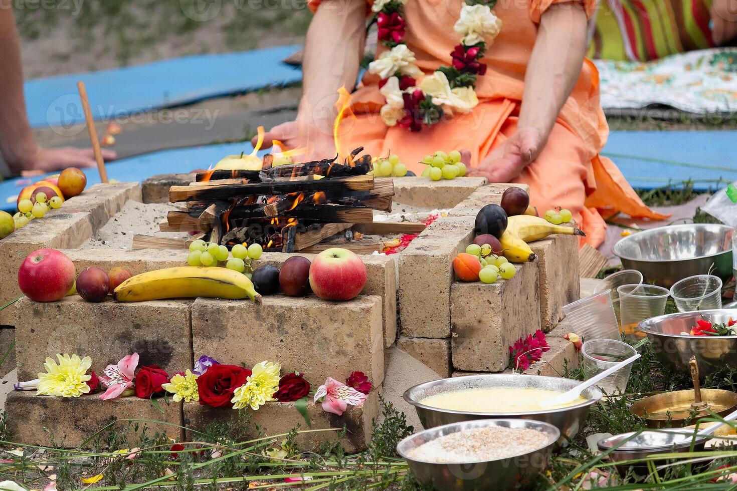 Krishnaids with fruit by the fire during the ritual photo