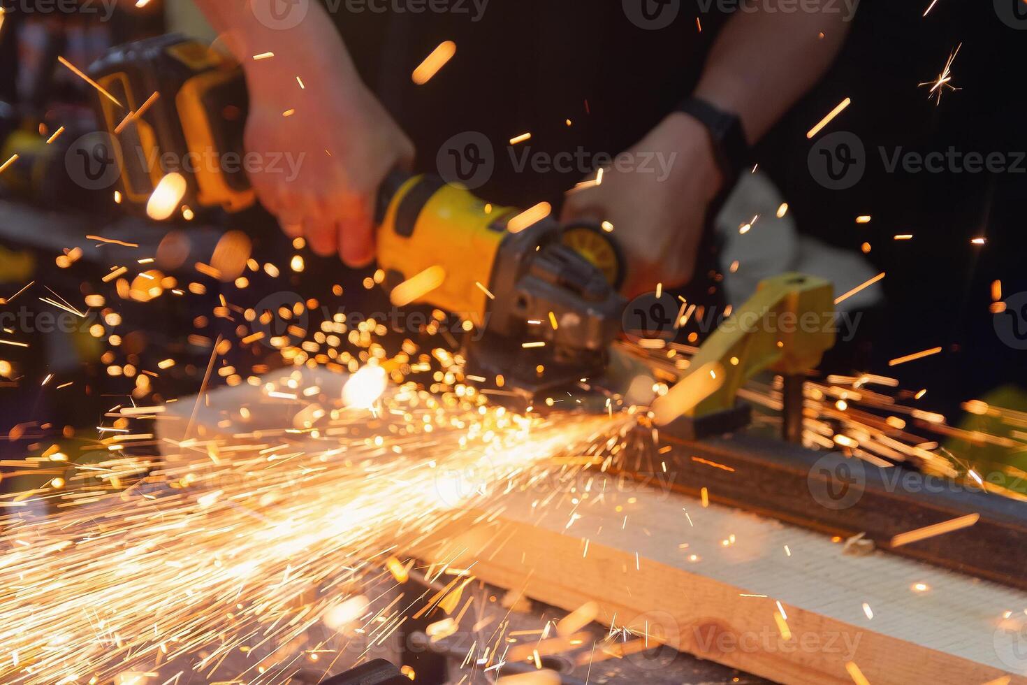 Craftsman using a grinder to cut metal in a workshop with sparks flying. Industry photo