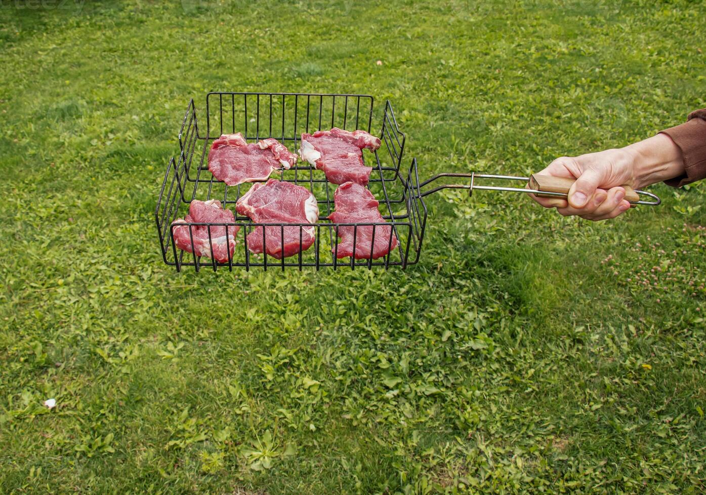 Meat beef steak barbecue on grill with smoke green grass background. photo